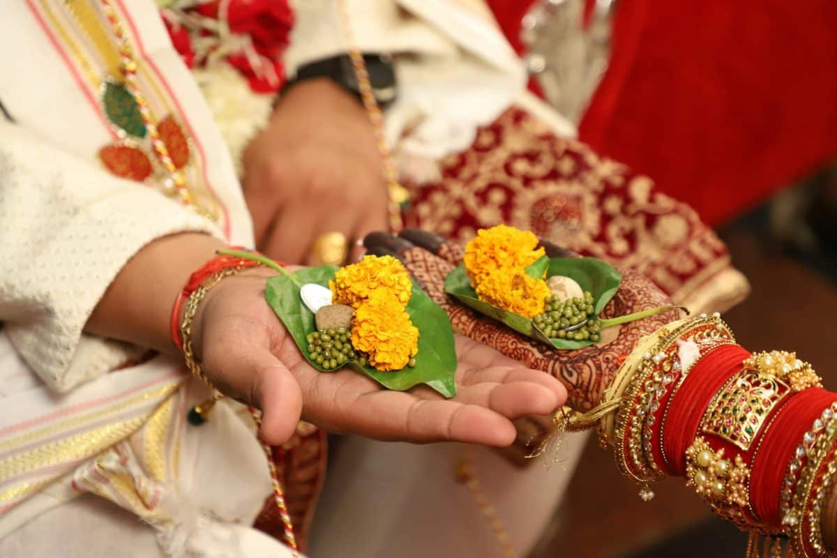 close up of bride and groom holding leaves with flowers on their hands